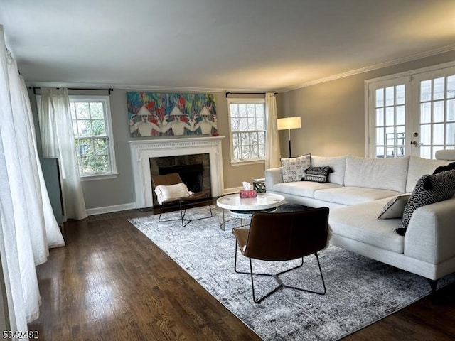 living area with baseboards, a fireplace with flush hearth, ornamental molding, wood finished floors, and french doors