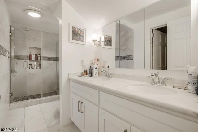 full bath with double vanity, marble finish floor, a shower stall, and a sink