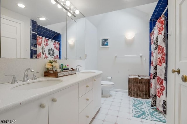 bathroom featuring toilet, double vanity, a sink, and tile patterned floors