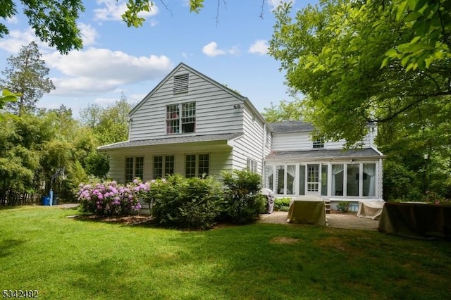 back of house with a yard, a patio, and a sunroom