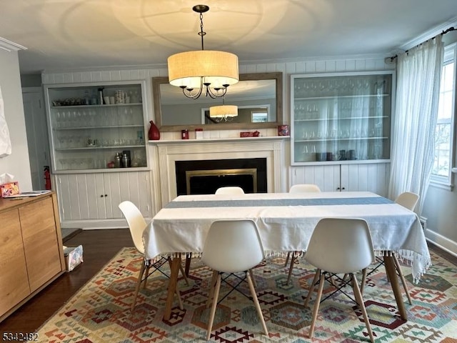 dining area featuring built in shelves, crown molding, a fireplace, and wood finished floors