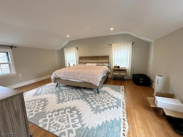 bedroom featuring lofted ceiling, baseboards, and wood finished floors