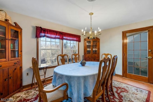 dining space featuring an inviting chandelier, baseboards, and wood finished floors