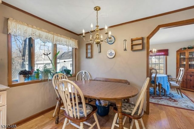 dining room featuring ornamental molding, an inviting chandelier, light wood-style flooring, and baseboards