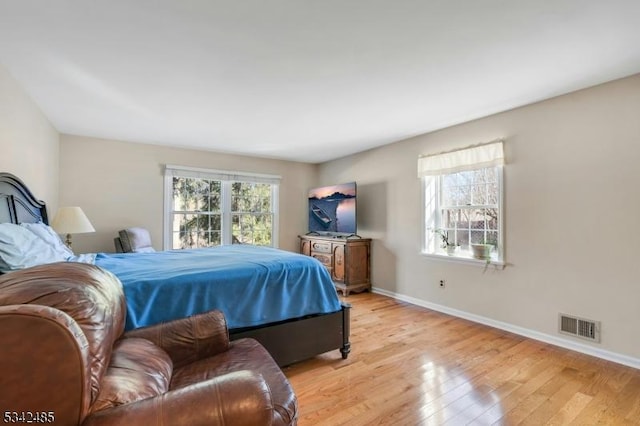 bedroom with light wood-style floors, baseboards, multiple windows, and visible vents