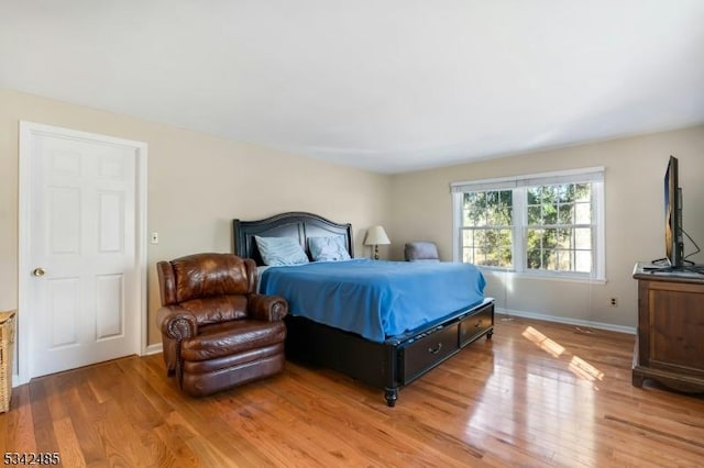 bedroom featuring light wood finished floors and baseboards