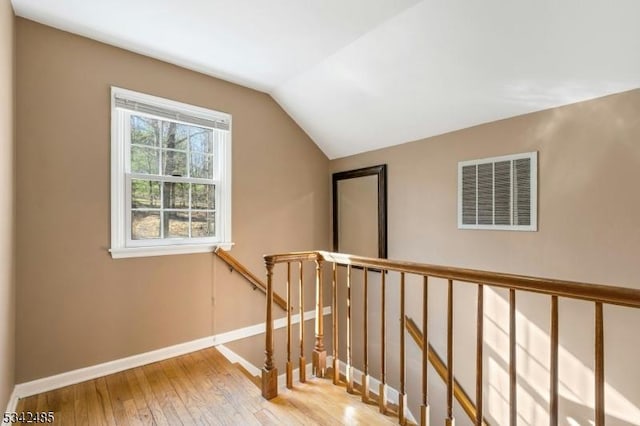 interior space featuring visible vents, vaulted ceiling, baseboards, and hardwood / wood-style flooring