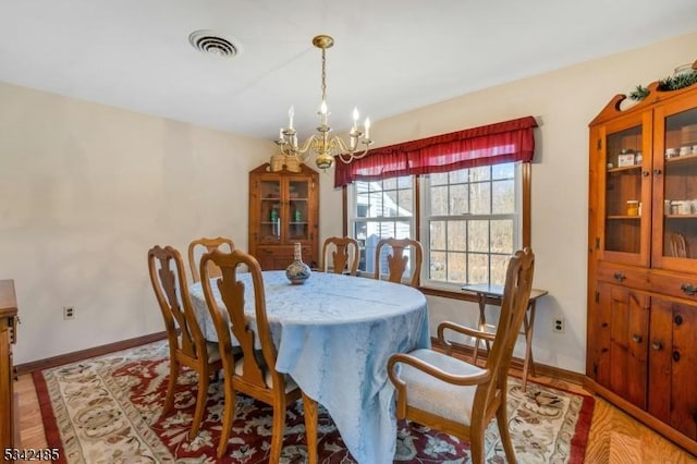 dining room with baseboards, visible vents, a chandelier, and light wood-style flooring