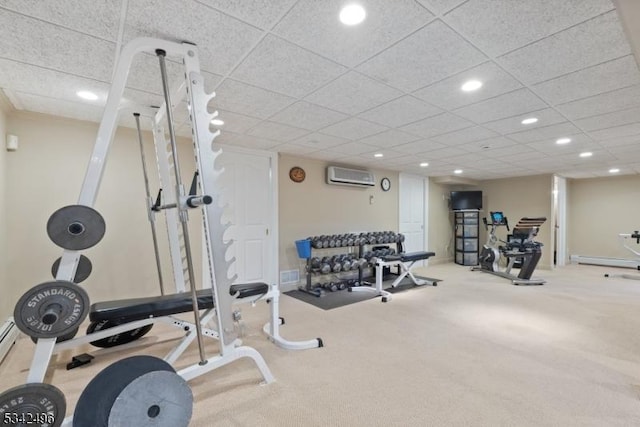 workout room with a wall unit AC, a drop ceiling, and recessed lighting