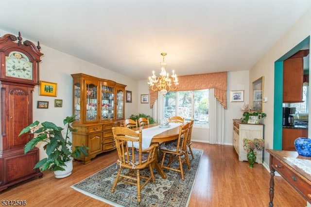 dining space featuring a notable chandelier, baseboards, and light wood-style floors