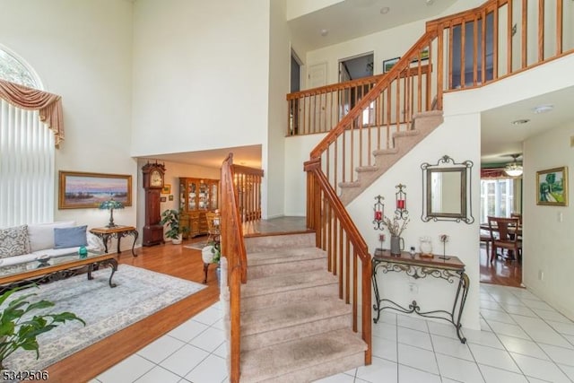 stairs featuring ceiling fan, tile patterned flooring, and a towering ceiling