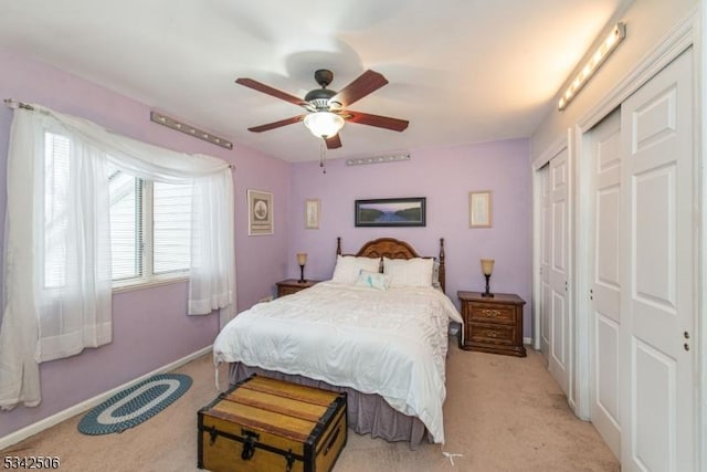 bedroom with ceiling fan, baseboards, two closets, and light colored carpet