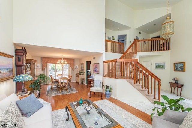 living room featuring a high ceiling, stairs, a chandelier, and wood finished floors