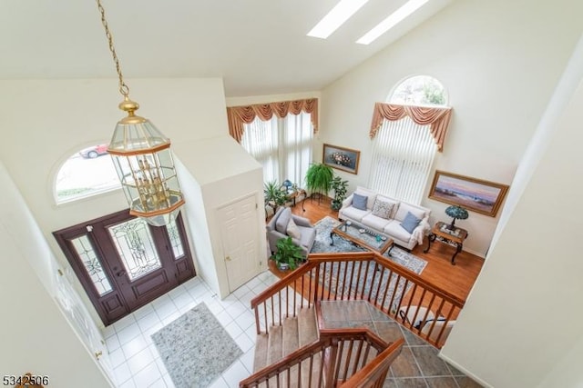 tiled entrance foyer featuring high vaulted ceiling and a skylight