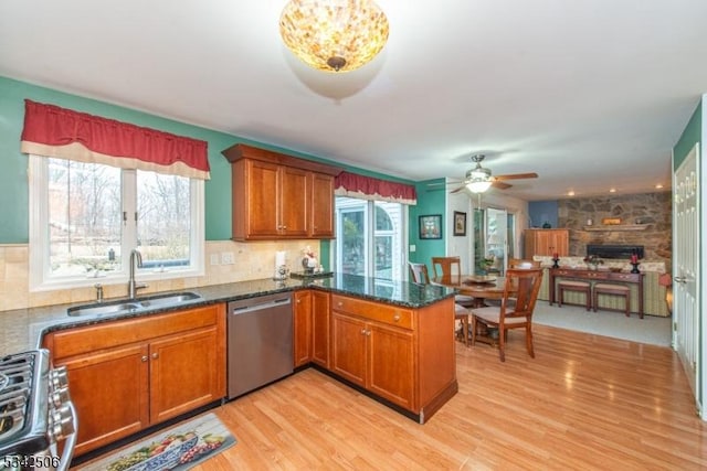 kitchen featuring appliances with stainless steel finishes, brown cabinetry, a sink, and a wealth of natural light