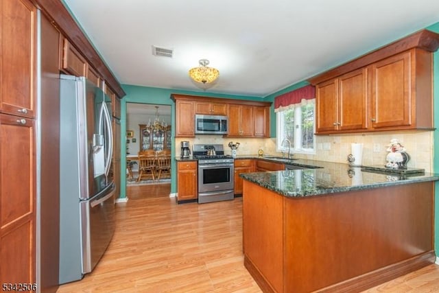 kitchen featuring brown cabinets, visible vents, stainless steel appliances, and a sink