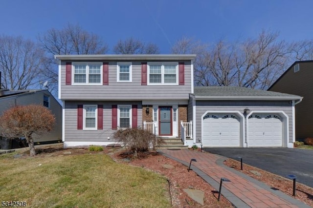 colonial home with aphalt driveway, a garage, and a front yard