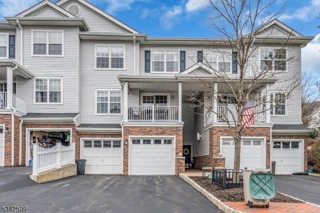 multi unit property featuring a garage, driveway, and brick siding