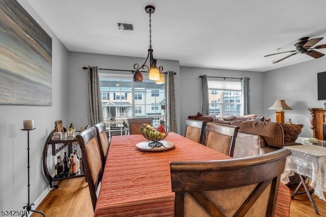 dining space with ceiling fan, light wood-style flooring, and baseboards