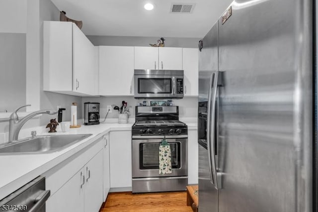 kitchen featuring visible vents, appliances with stainless steel finishes, light countertops, light wood-style floors, and a sink