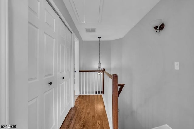 corridor with attic access, visible vents, an upstairs landing, and dark wood-style floors