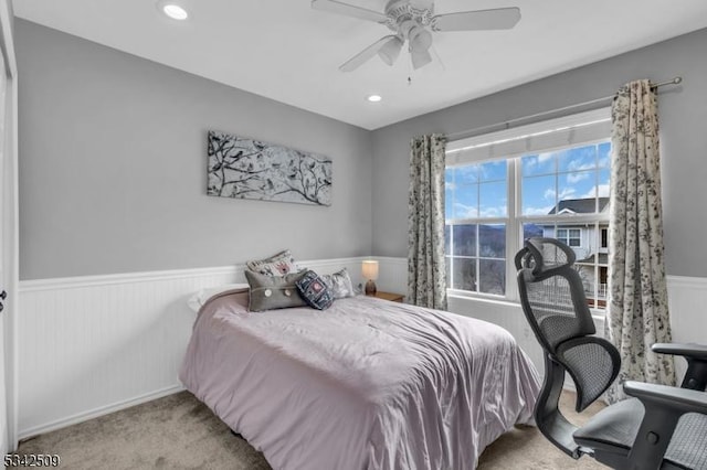 carpeted bedroom with a ceiling fan, recessed lighting, and wainscoting