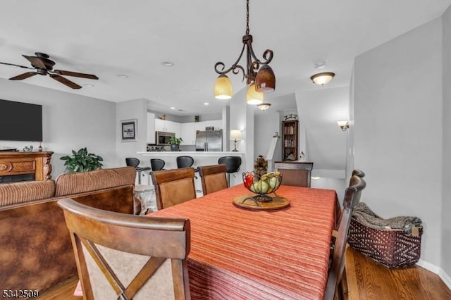 dining space featuring ceiling fan, baseboards, and wood finished floors