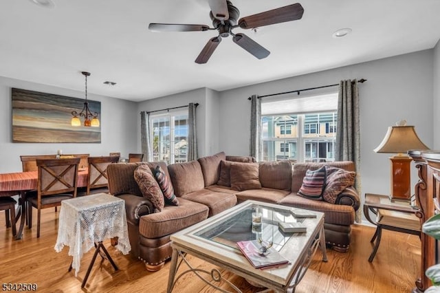 living area featuring light wood-type flooring, visible vents, and ceiling fan