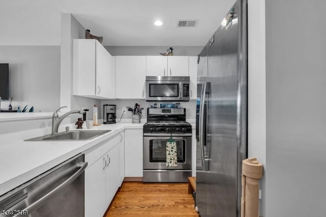 kitchen featuring stainless steel appliances, a sink, light countertops, and white cabinets