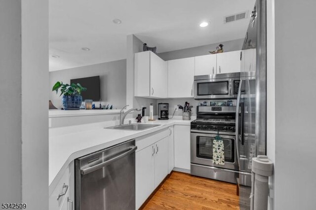 kitchen featuring stainless steel appliances, light countertops, visible vents, and a sink