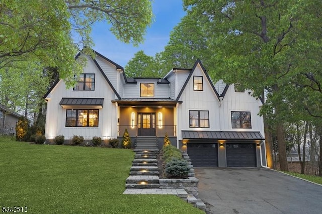 modern farmhouse style home with driveway, a standing seam roof, board and batten siding, and a front yard