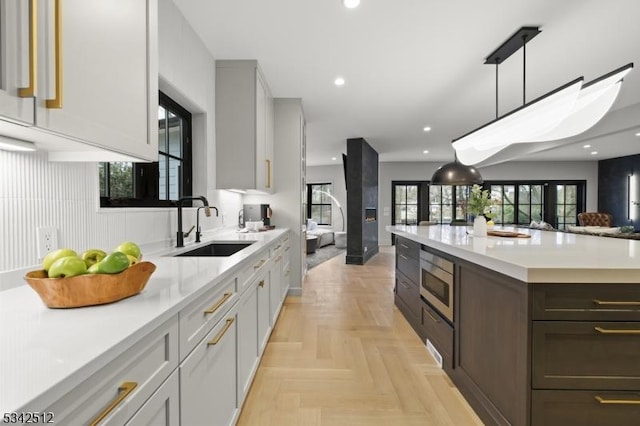 kitchen with recessed lighting, a sink, open floor plan, light countertops, and stainless steel microwave