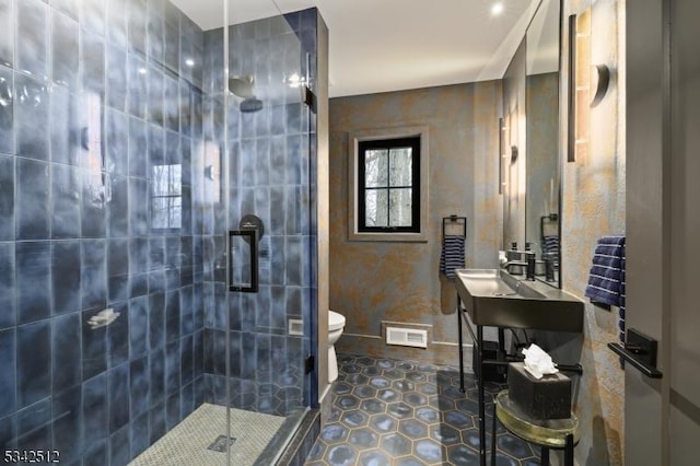 bathroom with visible vents, toilet, a tile shower, a sink, and tile patterned floors