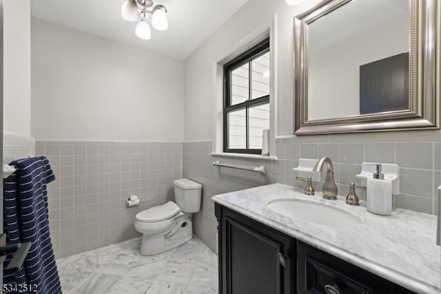 bathroom featuring tile walls, a wainscoted wall, vanity, and toilet