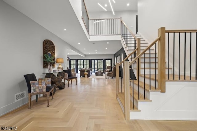 stairs featuring recessed lighting, visible vents, a towering ceiling, and baseboards