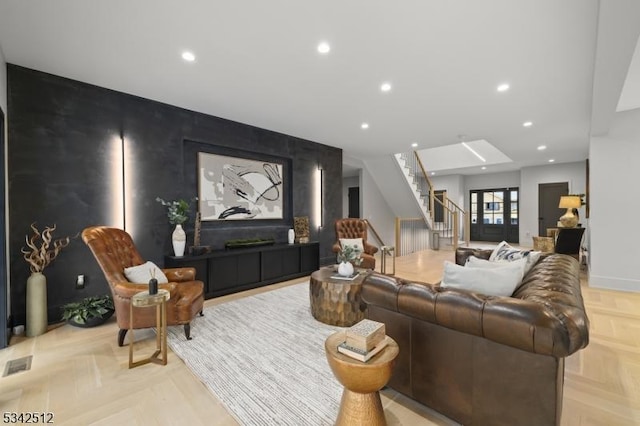 living area with an accent wall, stairway, visible vents, and recessed lighting