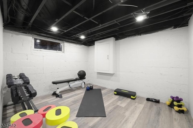 exercise room with electric panel and wood finished floors