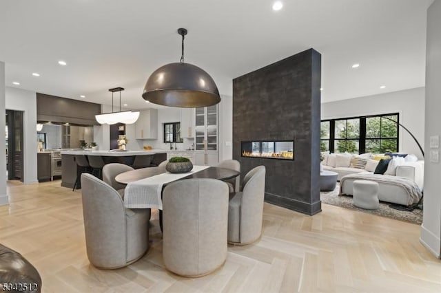 dining space featuring baseboards, a multi sided fireplace, and recessed lighting