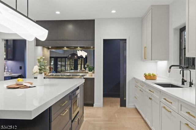 kitchen featuring stainless steel microwave, light countertops, pendant lighting, a sink, and recessed lighting