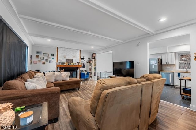 living area featuring beam ceiling, wood finished floors, a fireplace, and recessed lighting