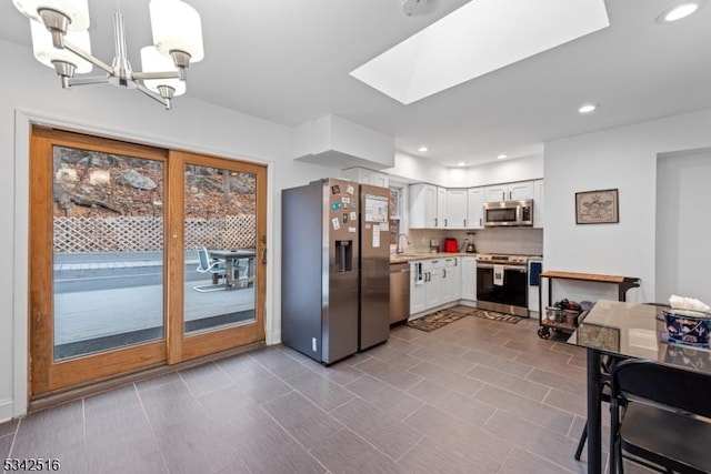 kitchen with a skylight, recessed lighting, light countertops, white cabinets, and appliances with stainless steel finishes