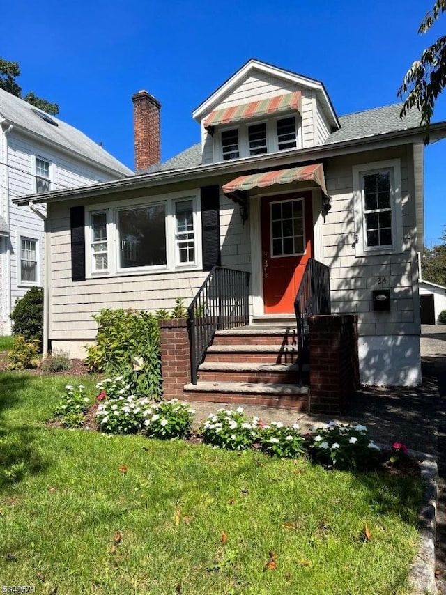 view of front of home with a front yard and a chimney