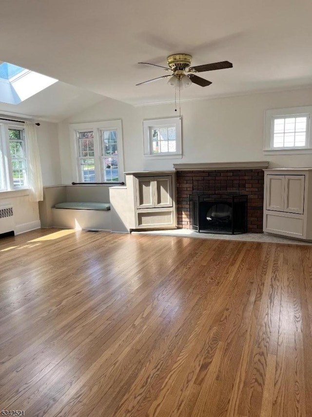 unfurnished living room featuring a healthy amount of sunlight, a fireplace, and radiator heating unit