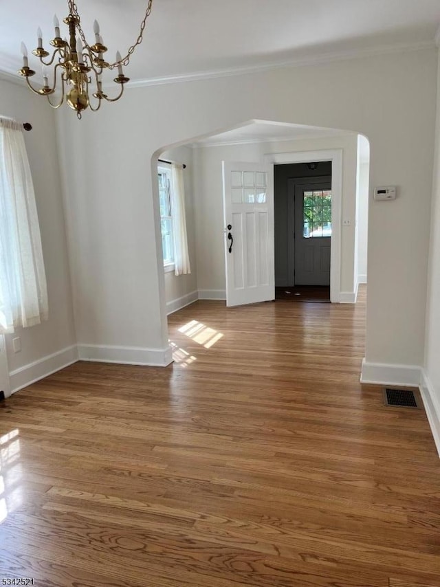 entryway with arched walkways, wood finished floors, visible vents, and crown molding