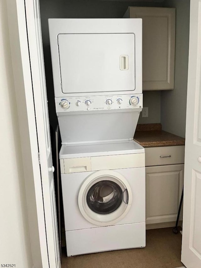 washroom featuring stacked washer / dryer and cabinet space