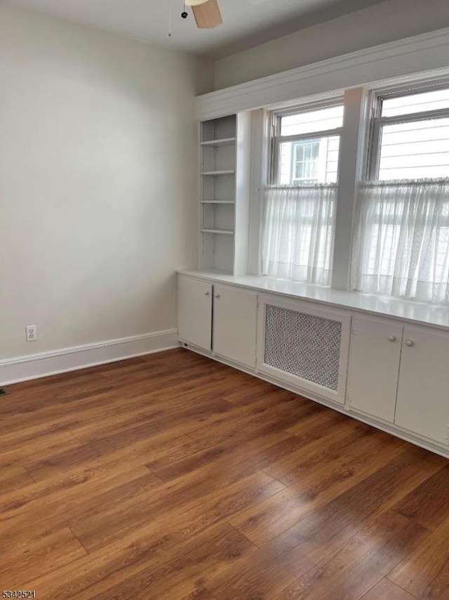 empty room featuring a ceiling fan, wood-type flooring, and baseboards