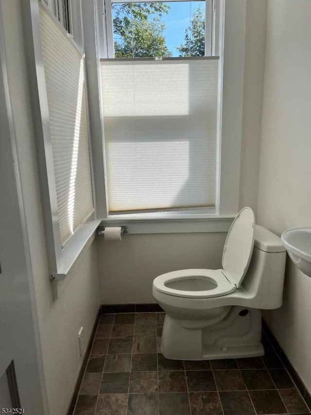 half bathroom with baseboards and toilet