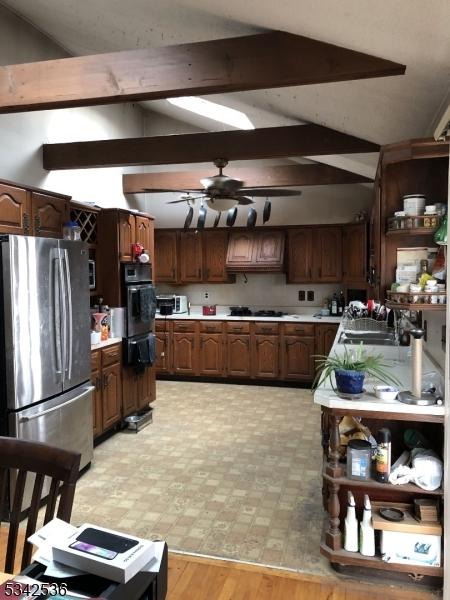 kitchen with open shelves, freestanding refrigerator, oven, a sink, and light countertops