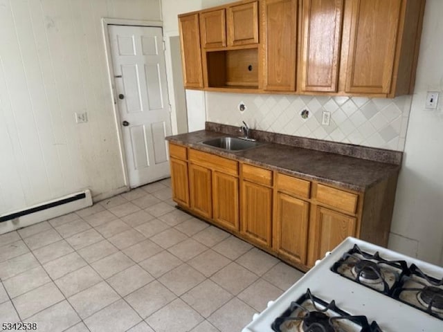 kitchen with dark countertops, decorative backsplash, a baseboard radiator, and a sink