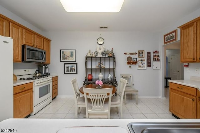 kitchen featuring light tile patterned floors, visible vents, white appliances, and light countertops